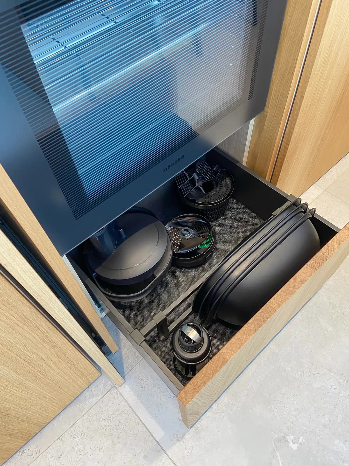 Lade onder de oven met zwarte schalen en keukentoebehoren